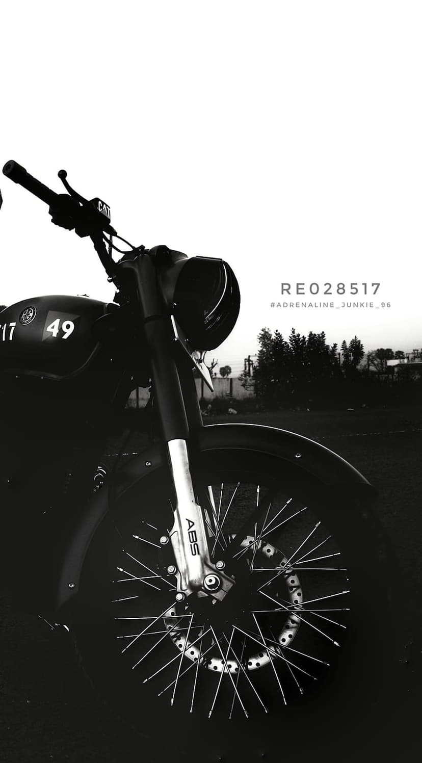 Front wheel and forks of a vintage Royal Enfield motorcycle featuring wire spokes and a black and white finish.