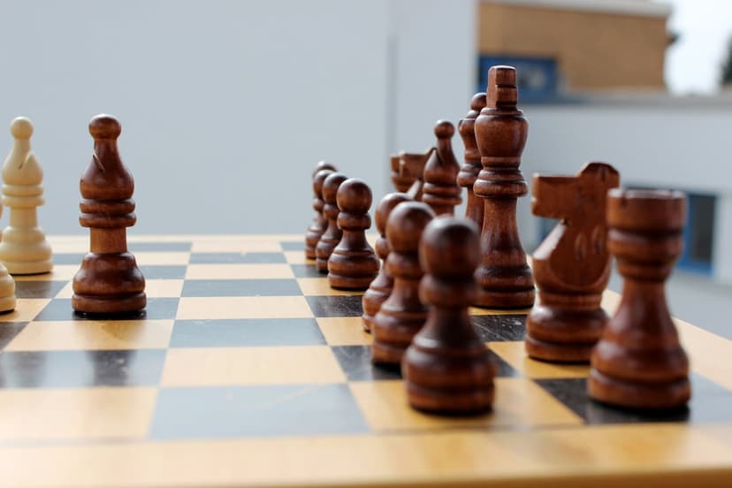 Wooden chess pieces arranged on a board with a blurred sky backdrop for a vertical phone screen wallpaper.