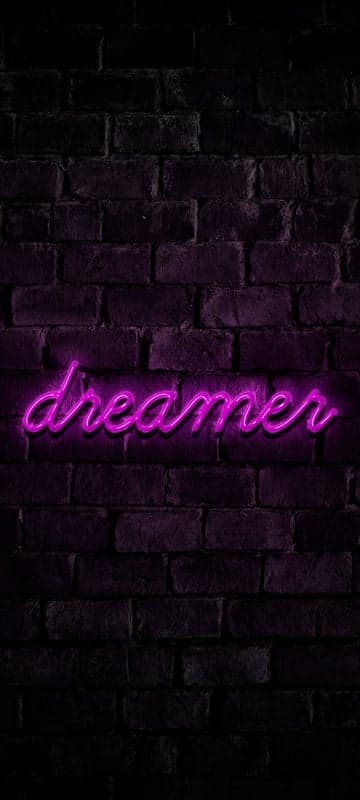 Purple Neon 'Dreamer' Sign on Dark Brick Wall