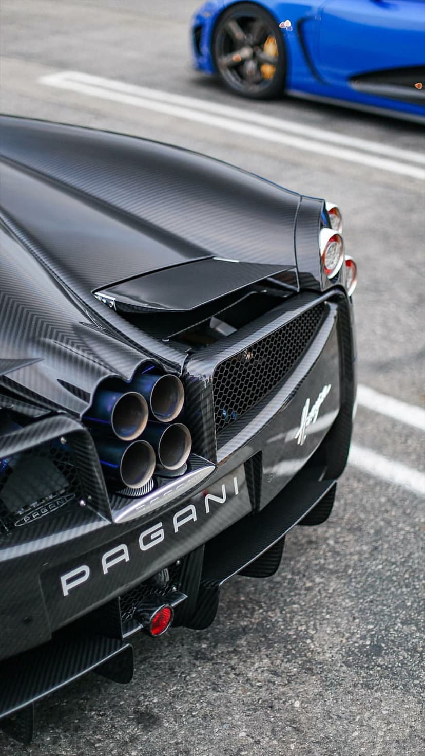 Pagani hypercar rear view featuring central quad exhaust pipes and dark carbon fiber bodywork details.