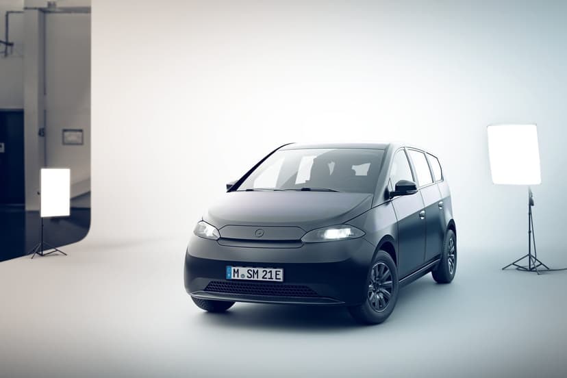 Matte grey solar electric vehicle in a bright white studio with soft lighting and a minimalist aesthetic.