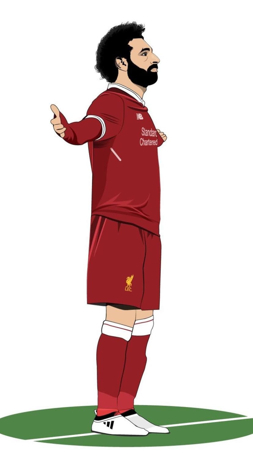 Bearded soccer player in a red kit gives a double thumbs up while standing on a small patch of green grass.