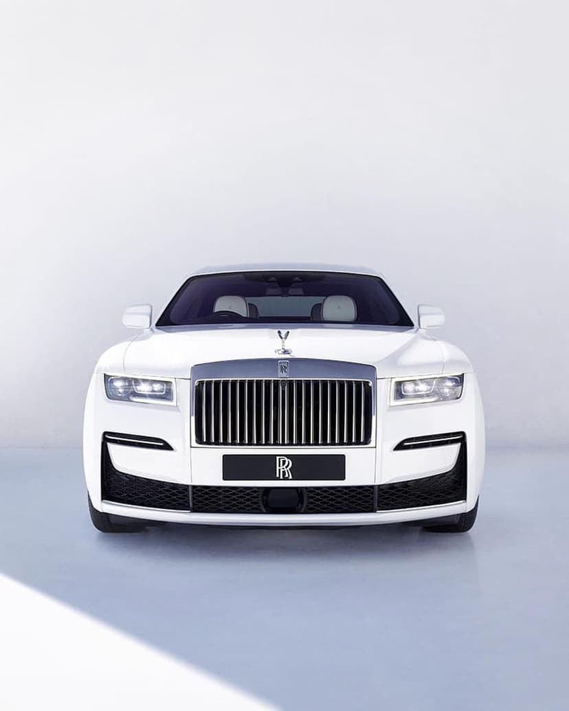 Rolls-Royce Ghost white luxury sedan showcasing a polished chrome grille and Spirit of Ecstasy hood ornament.
