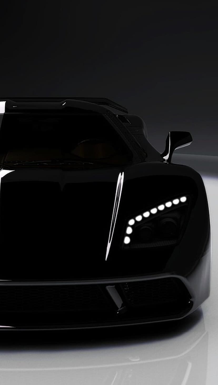Sharp LED headlights and a textured black grille of a luxury sports car reflecting subtle ambient light.