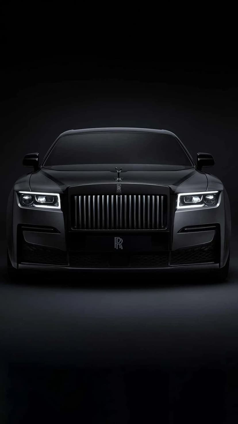 Black Rolls-Royce Ghost front grille with illuminated headlights and Spirit of Ecstasy mascot on the hood.