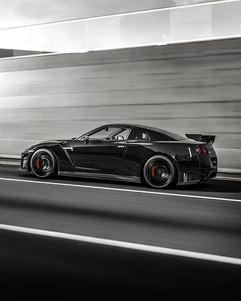 Black Nissan GT-R with red brake calipers speeds on a highway, featuring a rear spoiler and motion-blurred background.