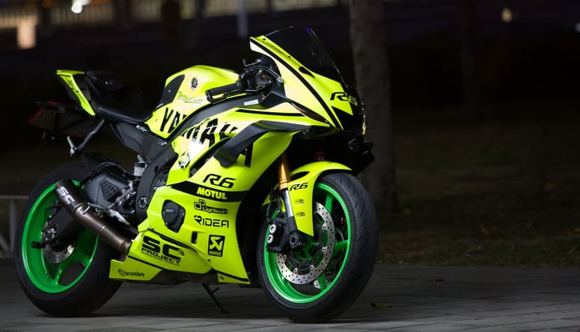 Neon yellow Yamaha R6 motorcycle with black graphics and green rim accents parked in a dark night environment.