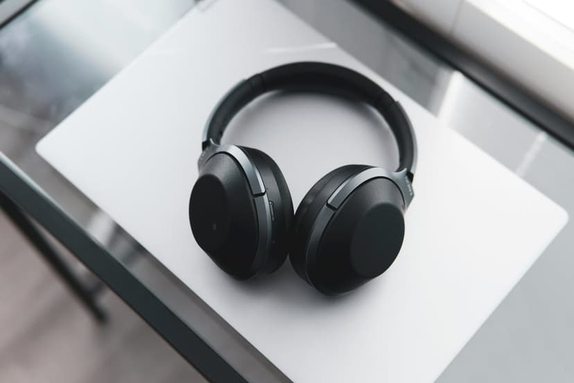 Black over-ear headphones resting on a white laptop lid with a blurred background in a minimalist workspace.