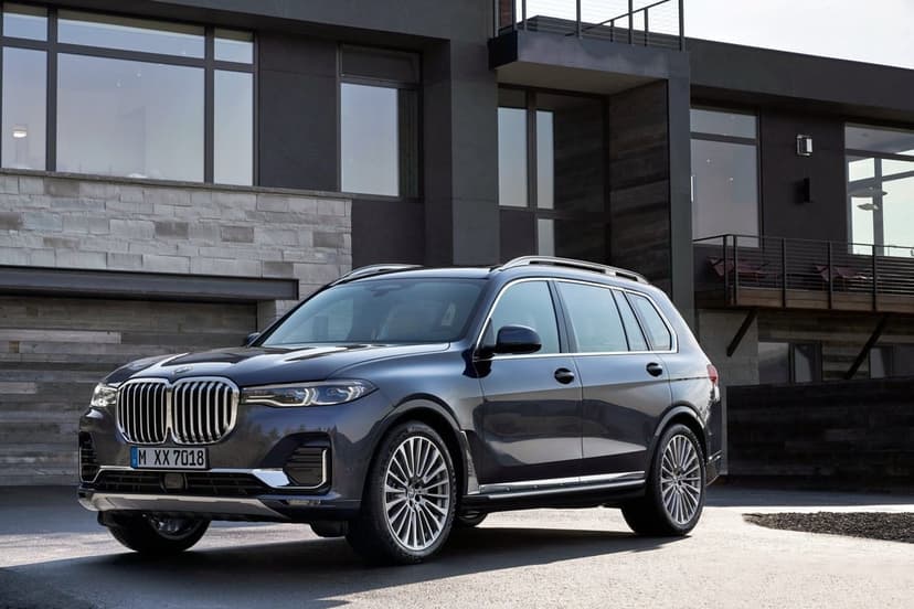 Dark blue luxury SUV parked in front of a modern dark gray house with large windows and stone walls.