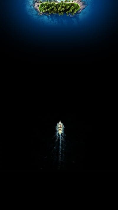 Lone boat travels through dark ocean towards tropical island