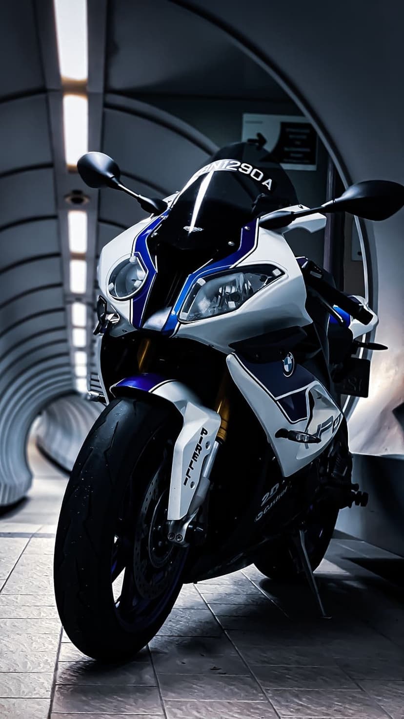 BMW S1000RR motorcycle in a white and blue livery parked inside a futuristic tunnel with curved architecture.