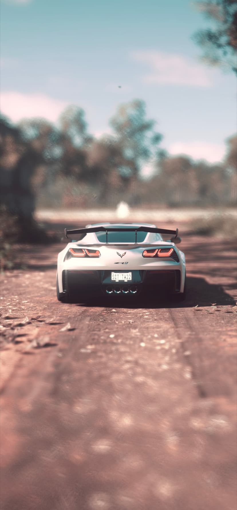 White Corvette ZR1 sports car driving on a dusty dirt road surrounded by trees during a golden sunset.