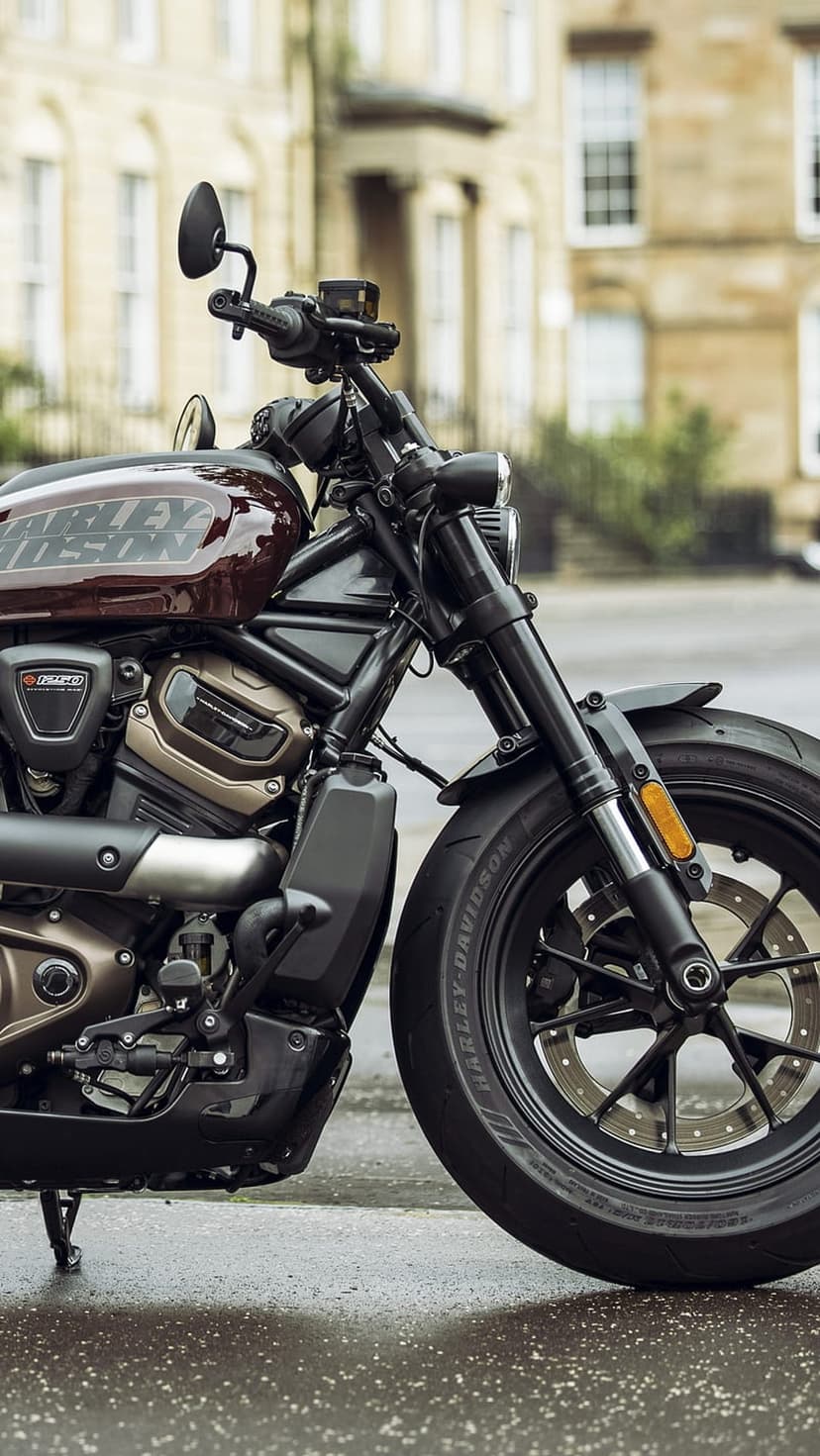 Harley-Davidson Sportster S motorcycle with a black engine parked on a wet city street by a classic building.