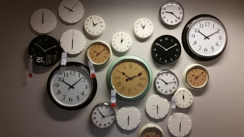 Overlapping analog wall clocks in various sizes and styles including minimalist and vintage Roman numeral designs.