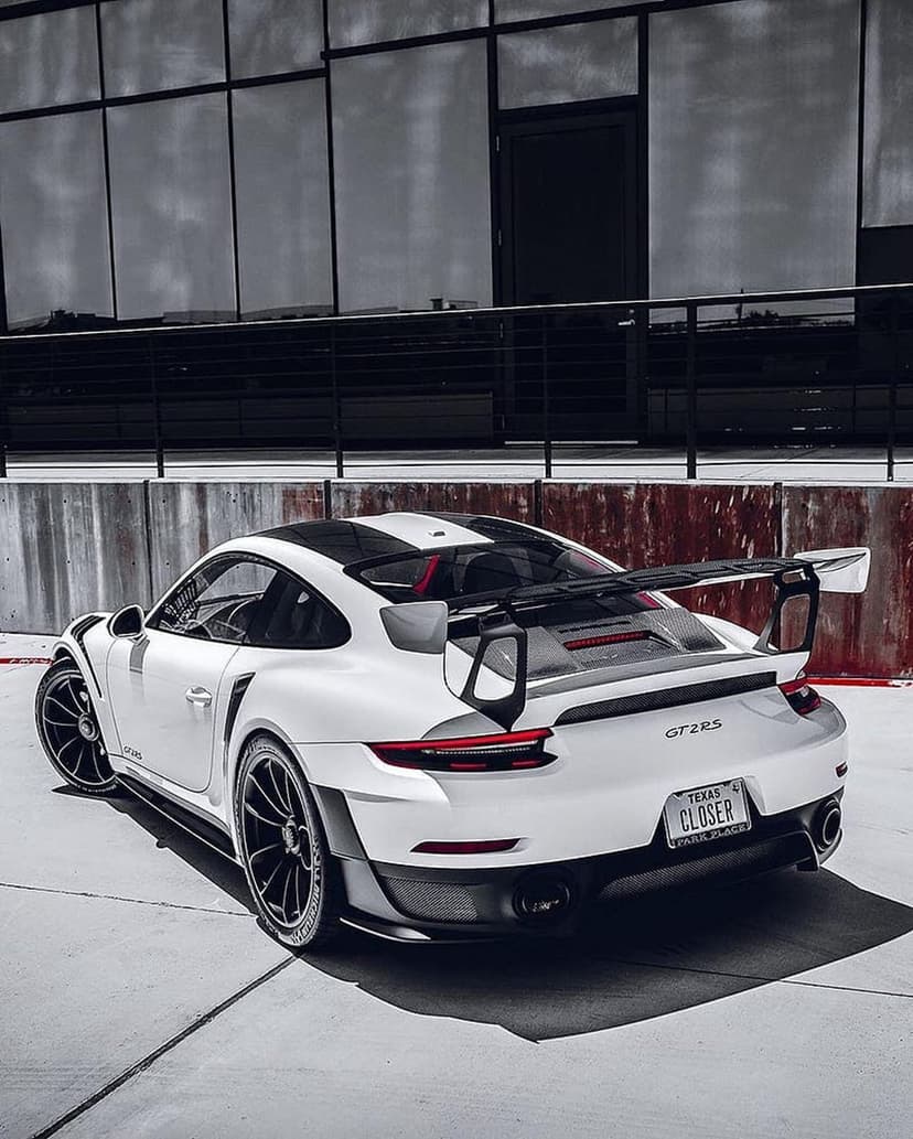White Porsche 911 GT2RS featuring a massive rear wing, black racing stripes, and carbon fiber trim accents.