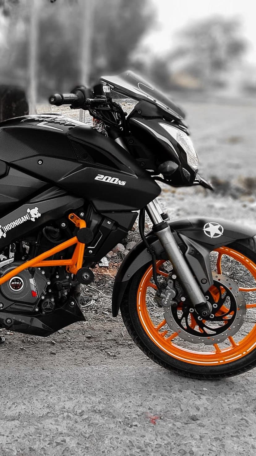 Black sportbike with orange alloy rims, front suspension forks, and engine guards against a blurred background.