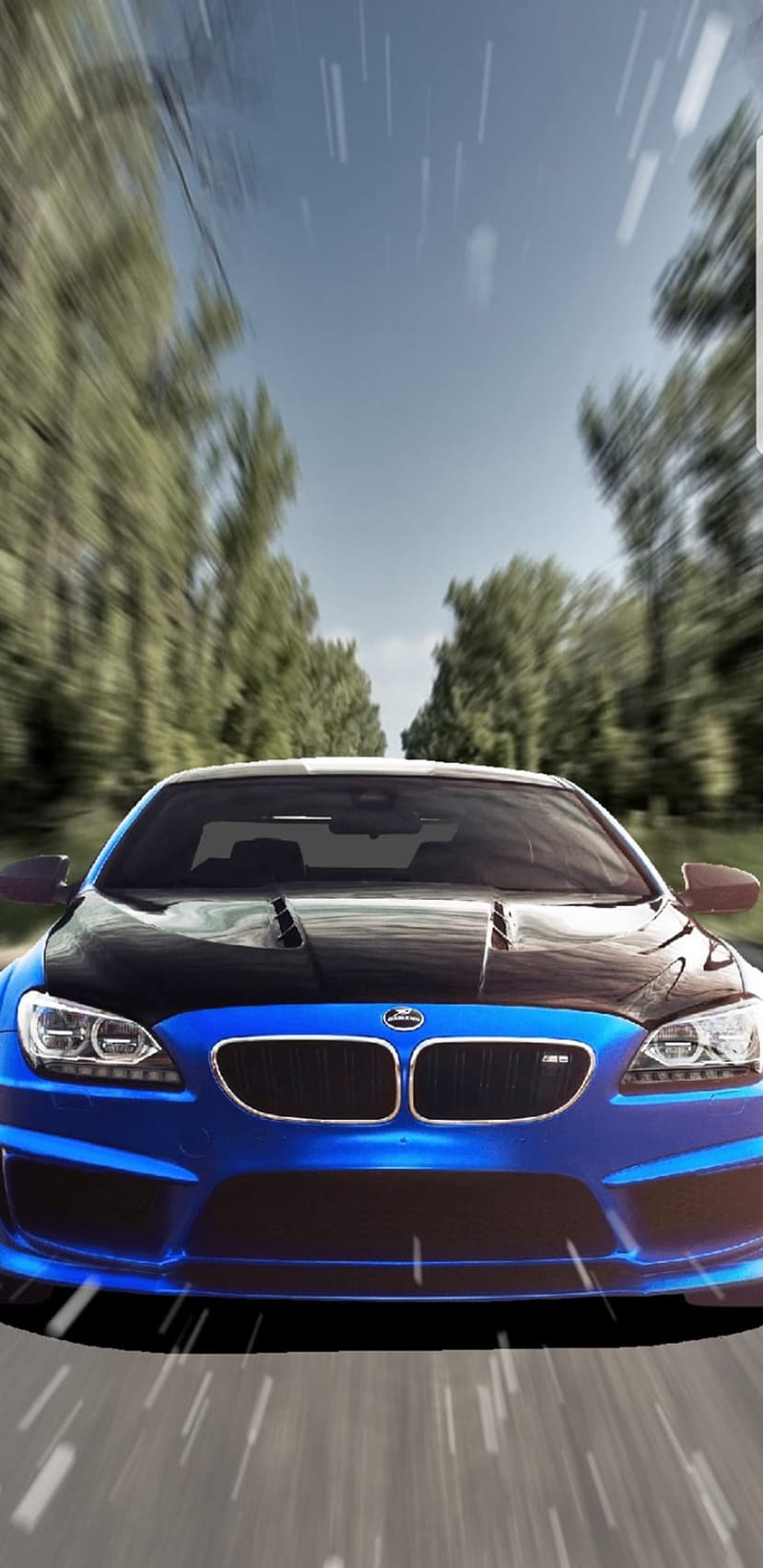 Blue BMW M6 coupe accelerates on a wet forest road with heavy motion blur and rainy streaks across the windshield.