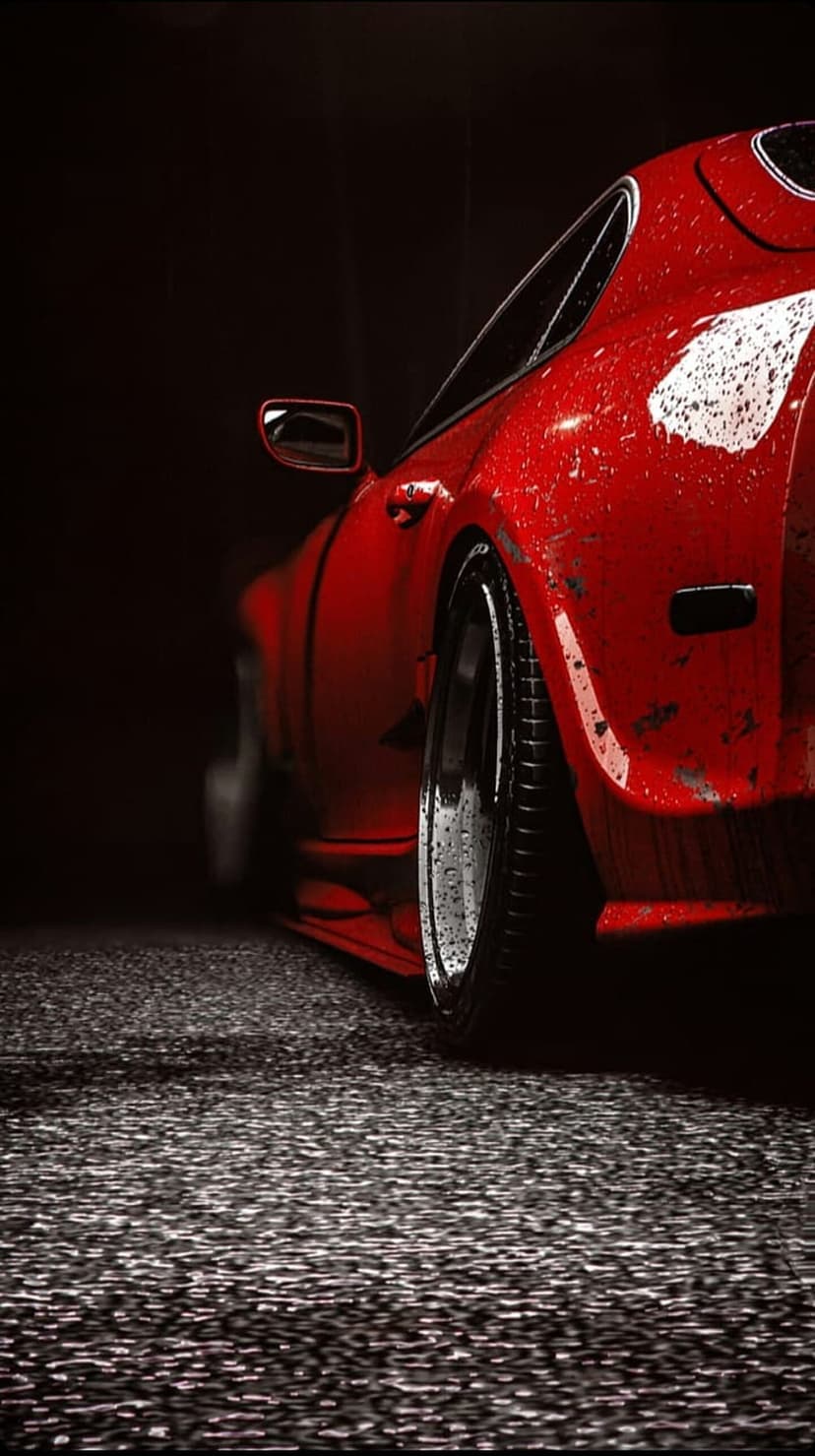 Crimson sports car with water droplets on its hood parked on a wet street at night with black alloy wheels.