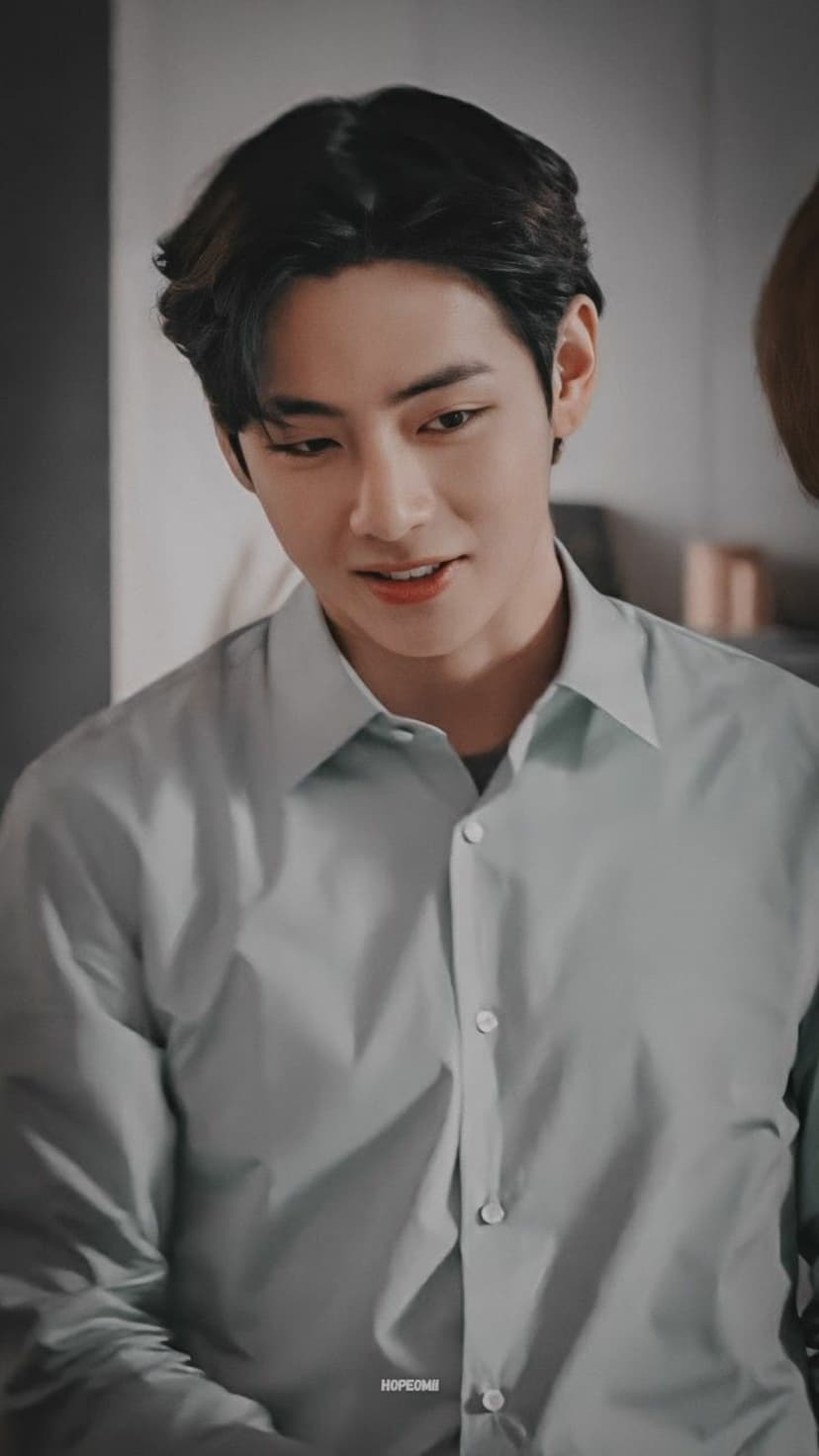 Kim Taehyung of BTS with dark hair and a gentle expression wearing a light blue collared shirt in a close-up view.