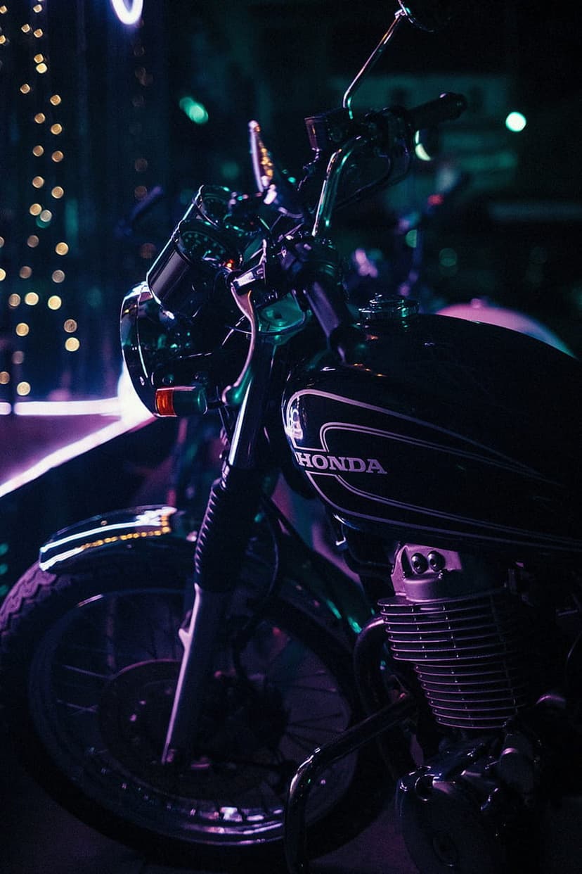 Black vintage Honda motorcycle with chrome engine parts illuminated by purple and green neon lights at night.