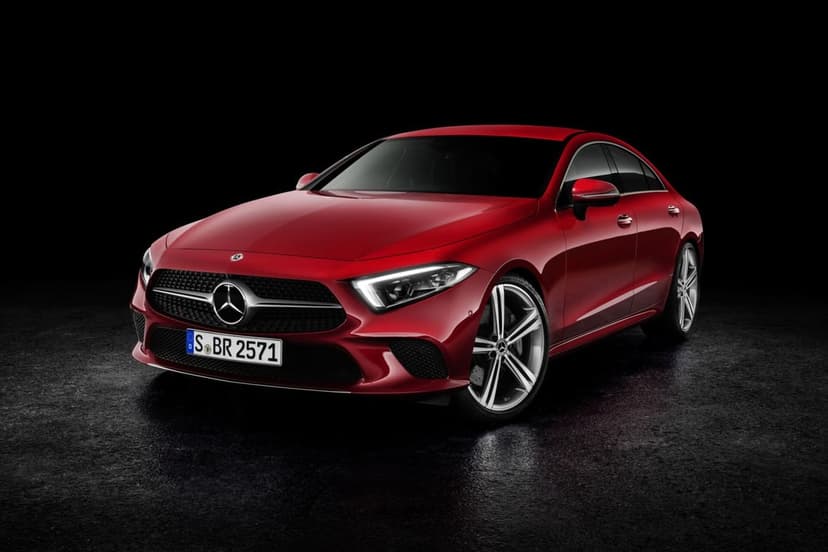 Front view of a red Mercedes-Benz CLS luxury car in a dark studio with glowing LED headlights and silver rims.