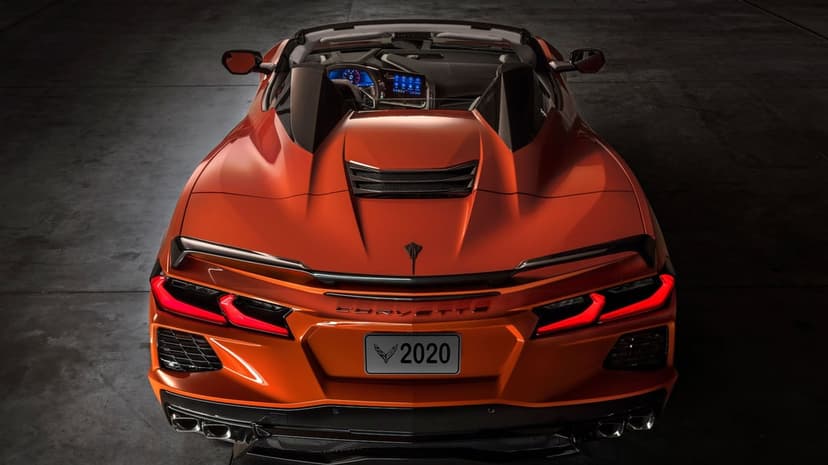 Rear view of a metallic orange 2020 Corvette C8 Stingray Convertible with glowing LED taillights and open top.