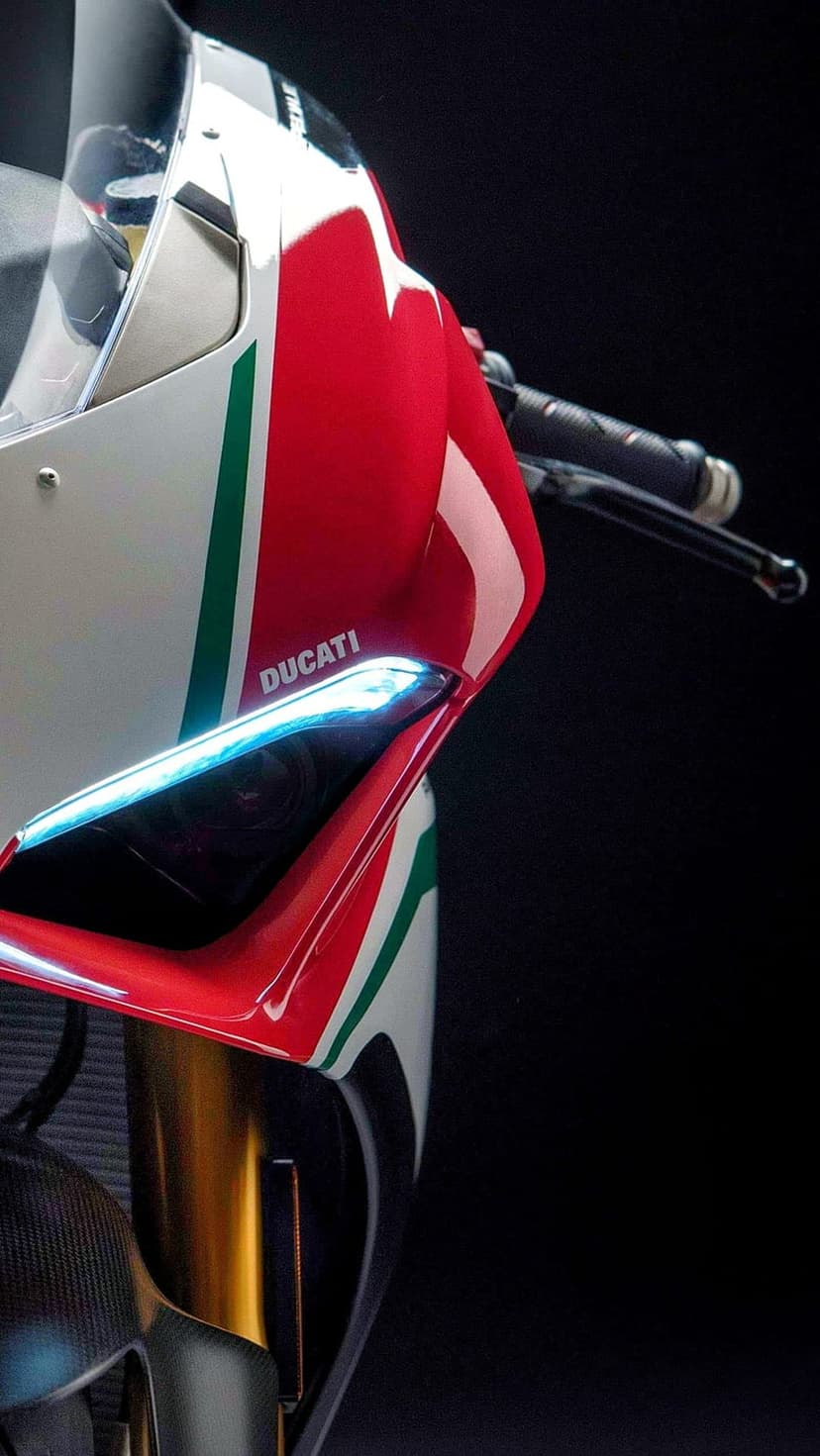 Red and white Ducati motorcycle fairing with a glowing headlight and green racing stripes on a black backdrop.