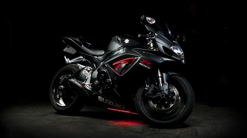 Matte black Suzuki GSX-R motorcycle with red LED lights against a dark background in landscape view.