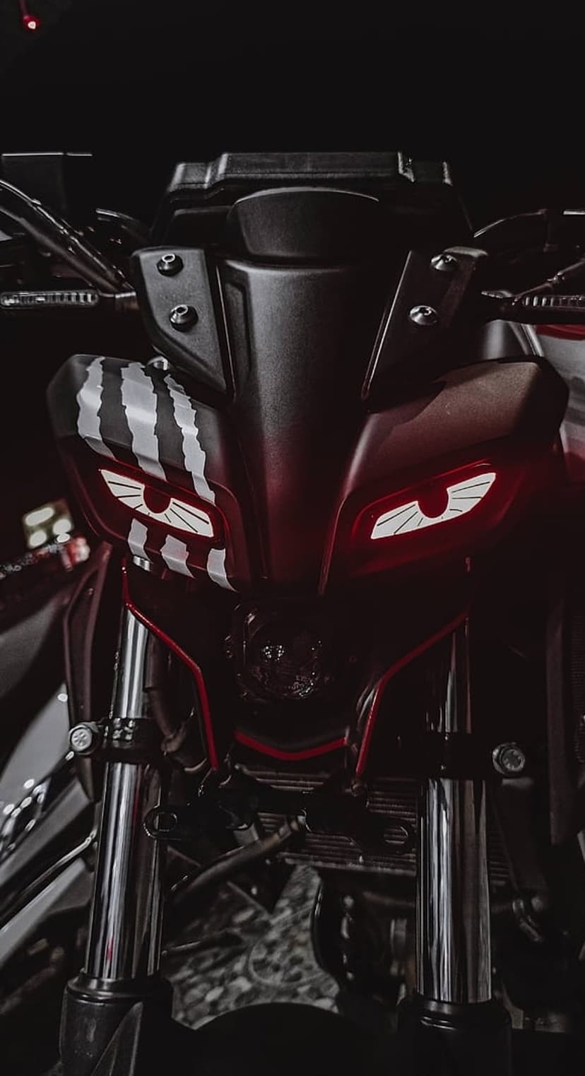 Yamaha MT motorcycle headlight with glowing red lamps, white Monster Energy decals, and black front forks.