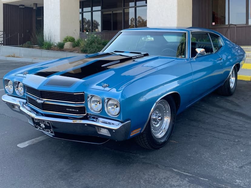 Blue 1970 Chevrolet Chevelle SS with black racing stripes and chrome wheels parked in a paved lot.