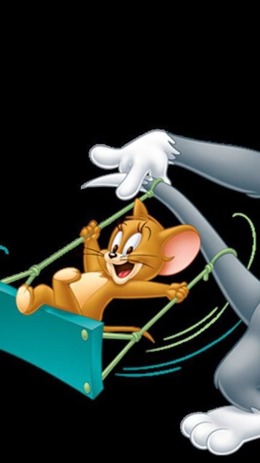 Jerry the mouse gleefully swings on a teal board held by Tom the cat’s grey paws against a solid black background.