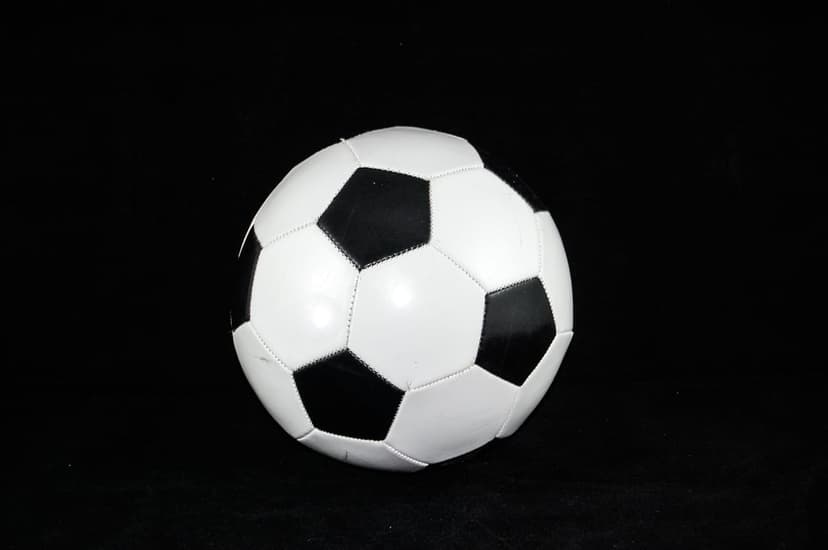 Classic soccer ball with hexagonal panels centered against a solid black background in a sharp portrait view.