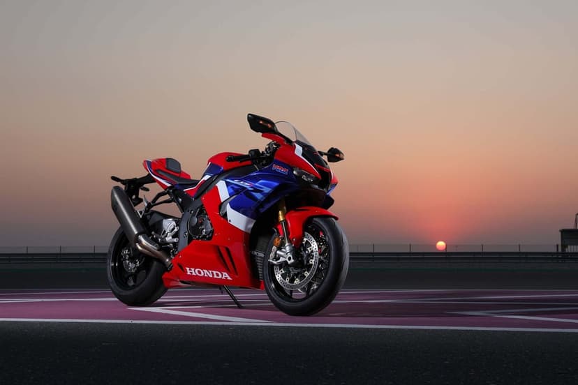Honda CBR1000RR-R Fireblade SP motorcycle on a racetrack at sunset under a pink and orange sky.