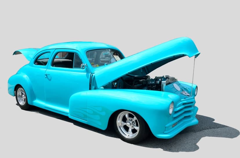 Turquoise vintage hot rod with its hood and trunk open to reveal a polished engine and custom car interior.