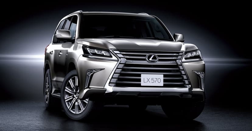 Silver Lexus LX 570 SUV parked against a dark studio background with cinematic side lighting.