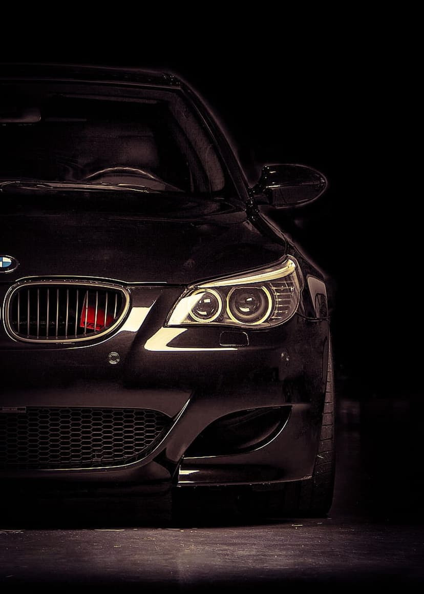 BMW M5 front end featuring glowing LED headlights and a black kidney grille with a small red accent badge.