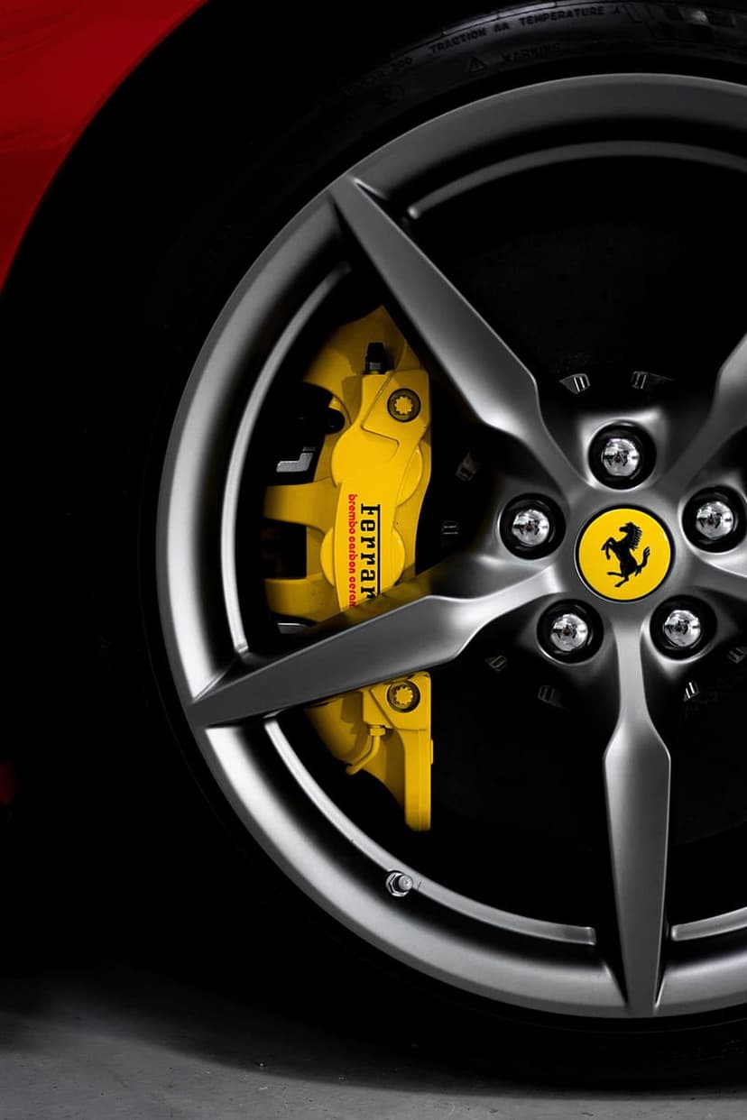 Bright yellow Ferrari brake caliper featuring the brand logo against a dark matte gray alloy wheel rim.