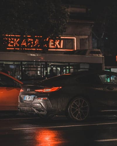 Rainy Night Cityscape with BMW and Neon Sign