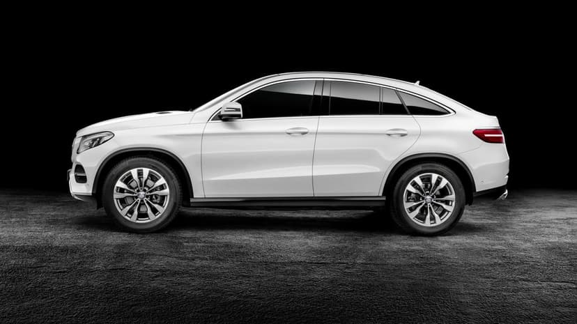 Side profile of a white Mercedes-Benz GLE Coupe on a dark textured surface against a solid black background.