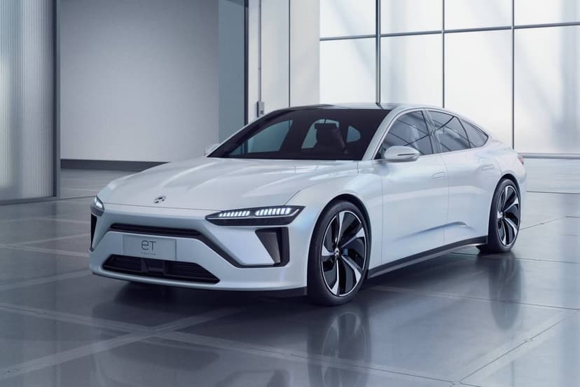 White NIO ET electric sedan concept in a glass showroom with soft lighting and reflective floors.