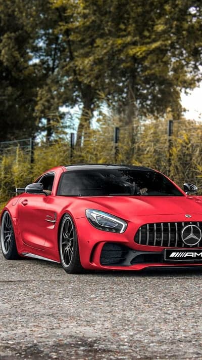 Red Mercedes-AMG GT S parked on gravel road with trees