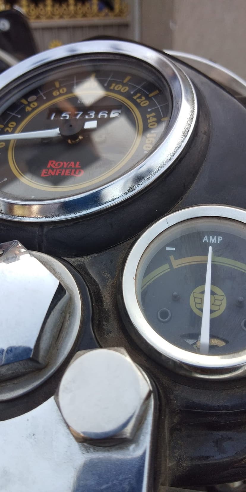 Royal Enfield speedometer and ammeter with chrome bezels and mechanical dials on a vintage motorcycle dashboard.