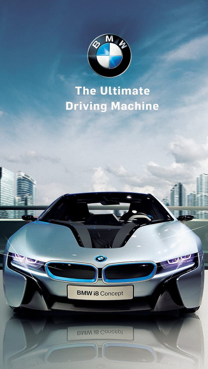 Silver BMW i8 hybrid supercar reflects city lights against a backdrop of modern glass skyscrapers at dusk.