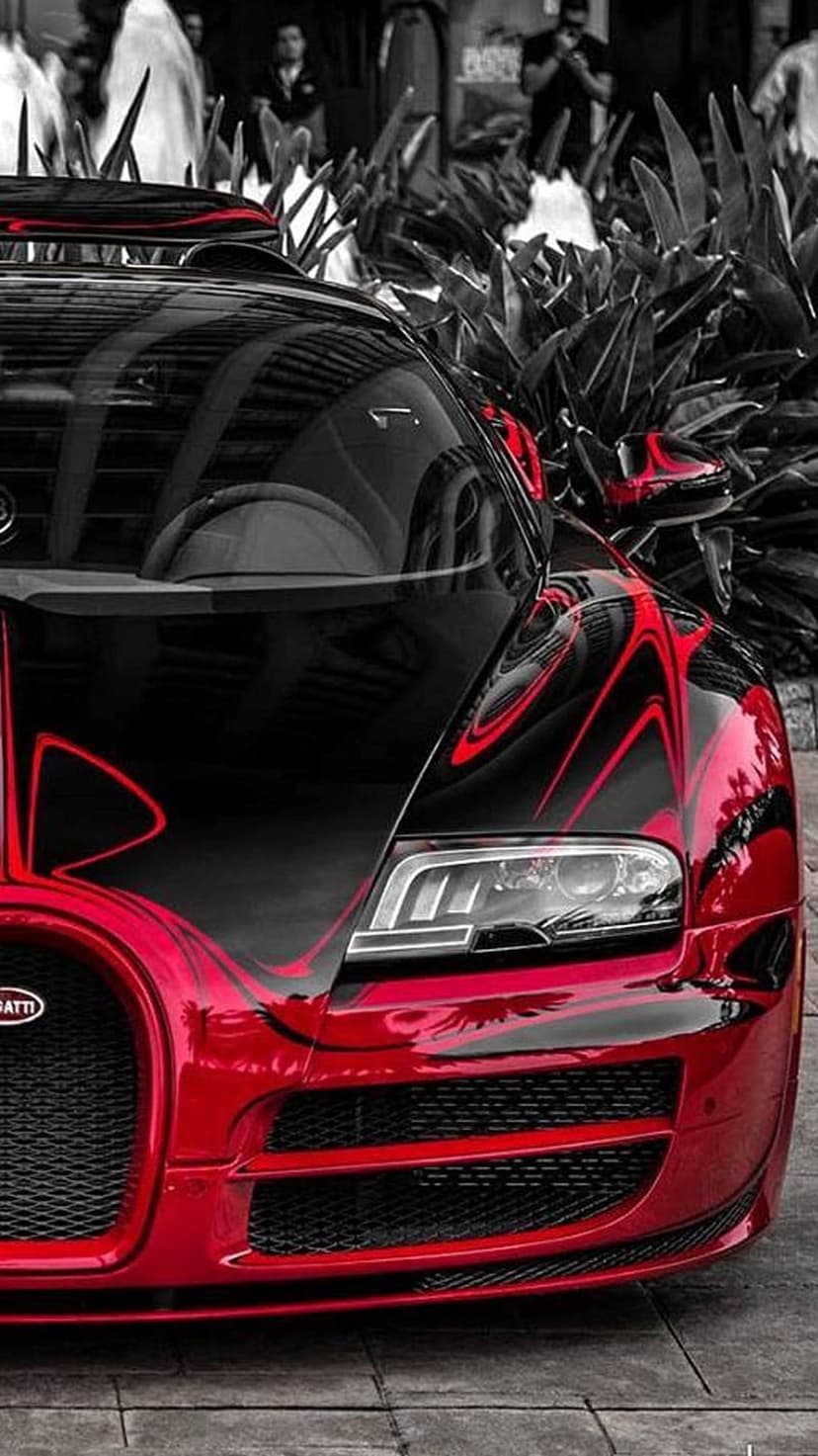 Bugatti Veyron front grille with red racing stripes and LED headlights against dark green leaves in the background.