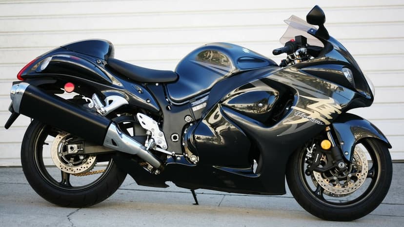Glossy black Suzuki Hayabusa sportbike shown in profile against a clean white slatted garage door background.