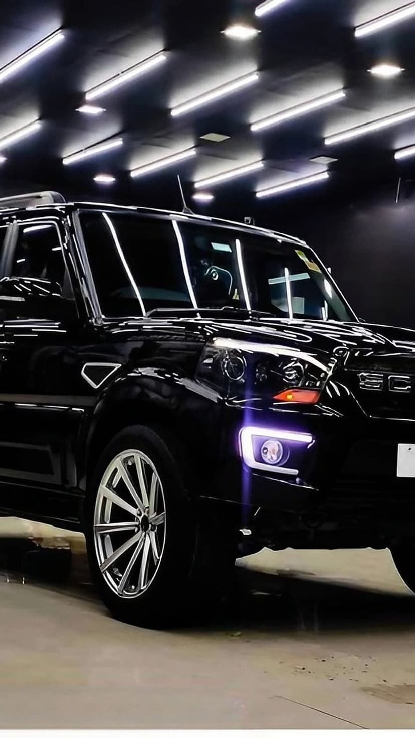 Mahindra Scorpio-N SUV in black sits in a dark studio with glowing LED headlights and custom alloy wheels.