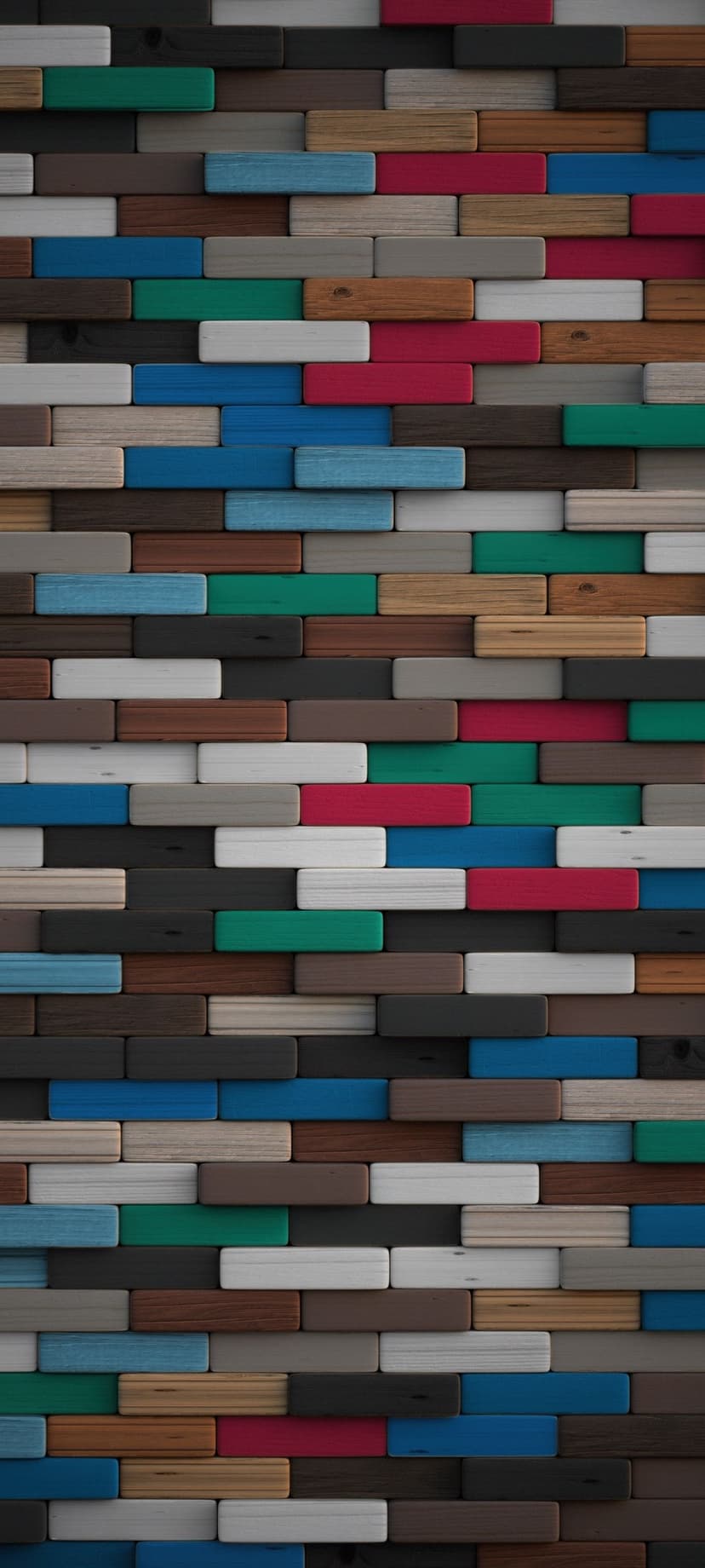 Staggered wooden blocks in shades of blue, red, and green showing natural grain in a dense geometric mosaic.