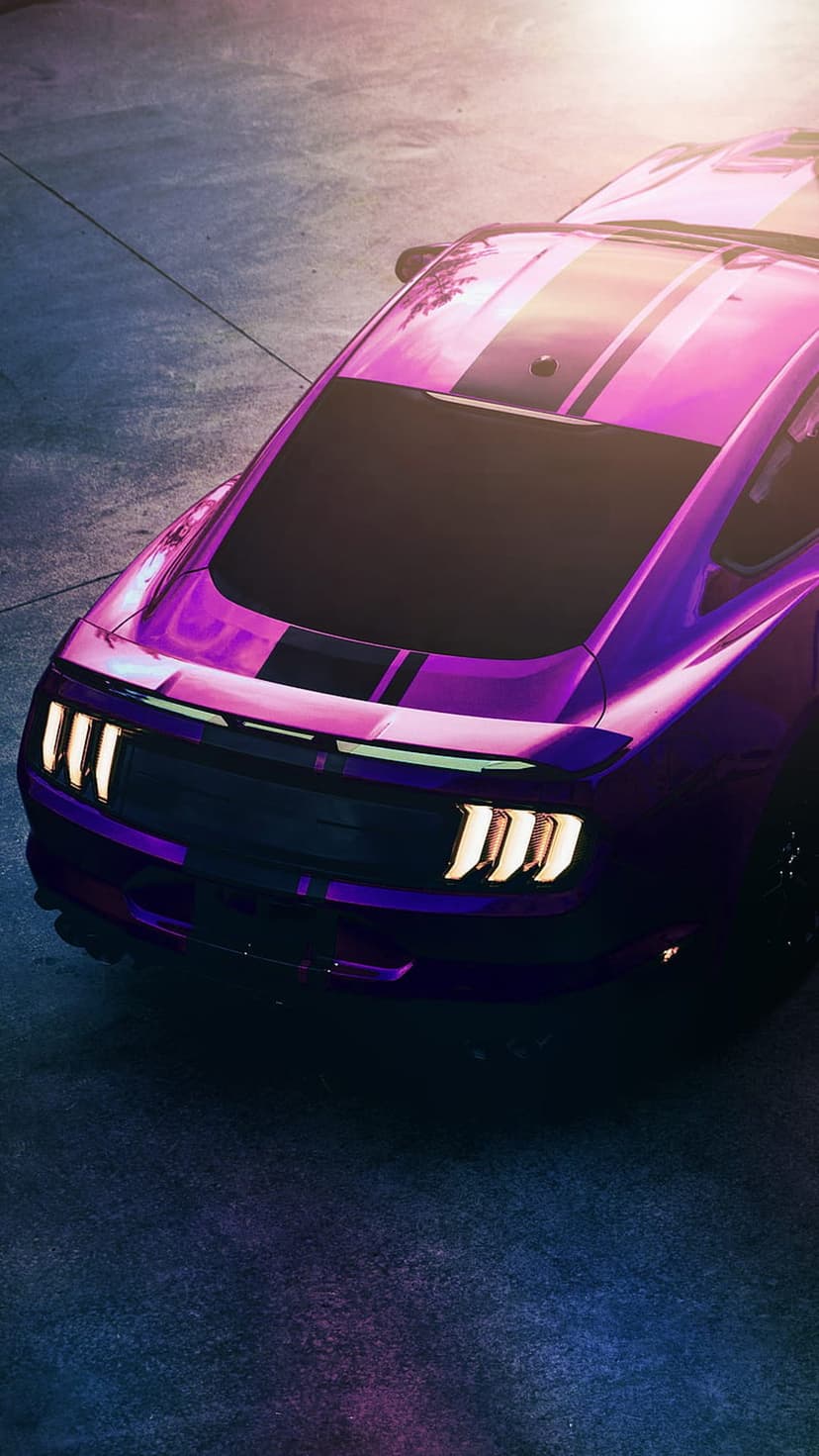 Purple Ford Mustang GT with racing stripes viewed from above on wet asphalt under dramatic night lighting.