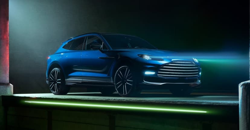 Blue luxury SUV on a dark industrial platform with neon green accents and glowing headlights in landscape view.