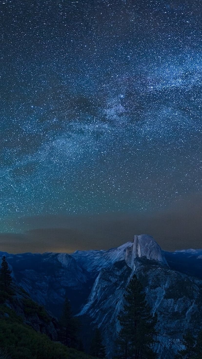 Half Dome granite peak silhouetted against a vibrant Milky Way galaxy and starry night sky in Yosemite Valley.